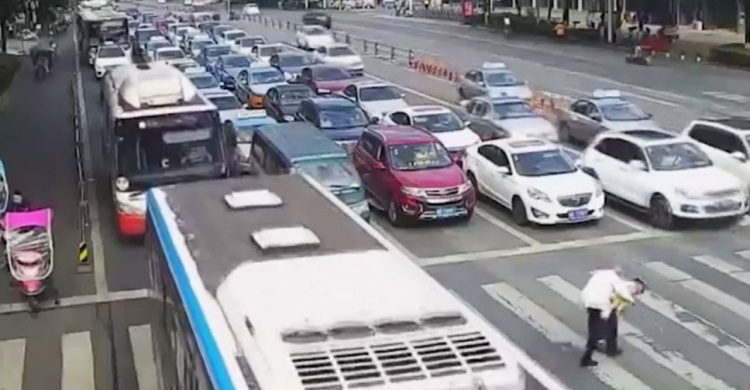 Пожилой китаец не успел перейти через автотрассу. Полицейский перенес его на себе (ВИДЕО)