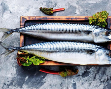 Скумбрія свіжа, готова до приготування на дошці з зеленню - фото з відкритих джерел