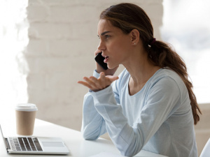 Дівчина говорить телефоном, на столі ноутбук та кава - фото з відкритих джерел