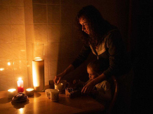 На фото: мати з дитиною запалюють свічку, фото з відкритих джерел 