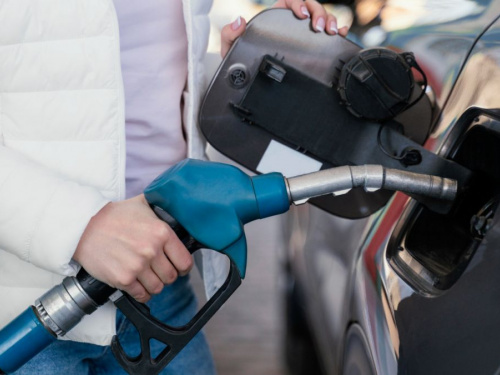 Жінка в білій куртці заправляє чорне авто - фото з відкритих джерел